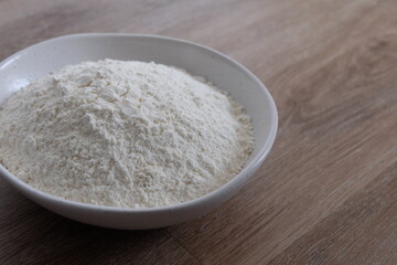 Flour in a white stone bowl with a wood background