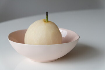 Peeled and cut nashi pear fruit in pink bowl