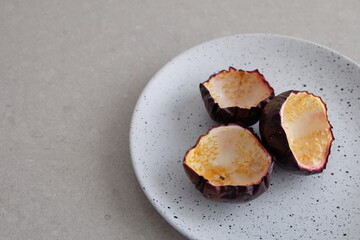 Peeled passionfruit shells on a spotted white and black plate with a grey stone table background