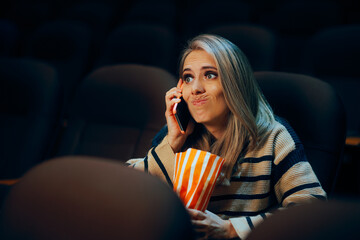 Woman Talking on the Phone in a Movie Theater. Rude moviegoer disrespecting the rules about...