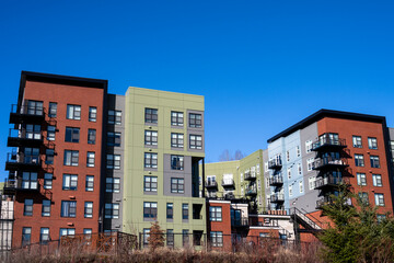 Modern mixed used building complex, business, apartment, and condo units, sage green, light blue, rust orange, and gray painted, sunny winter day
