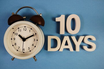 10 Days alphabet letters with alarm clock on blue background