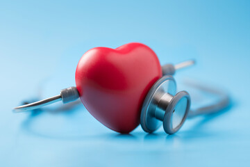 Red heart shape exercise ball with doctor physician's stethoscope on blue background, hospital life...