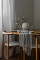 Festive Easter setting - Easter bouquet in a ceramic vase, dishes on a round wooden table in the living room