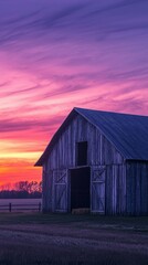 Obraz premium Rustic Wooden Barn Under Vibrant Sunset in Rural Landscape