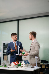  Professionals for a greener future. Showcasing renewable energy solutions with solar panels, wind turbines, and a model house.