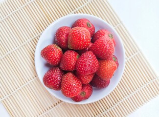 Close-up of strawberries in a small white plate. Top of view. 