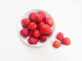 Directly above shot of strawberries in a small white plate on a white background. 