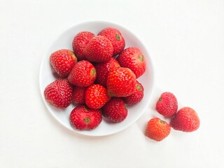 Directly above shot of strawberries in a small white plate on a white background. 
