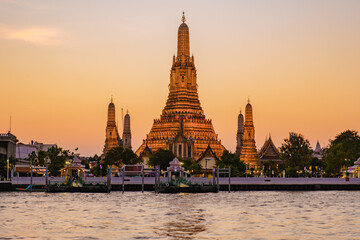 Fototapeta premium Majestic Wat Arun illuminated by sunset over Chao Phraya River in Bangkok Thailand