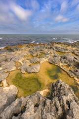 Wide angle shot of the sea and rocks with puddles in them