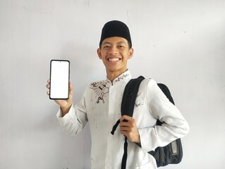 Asian Muslim man smiling happily while holding bag and showing blank cell phone screen