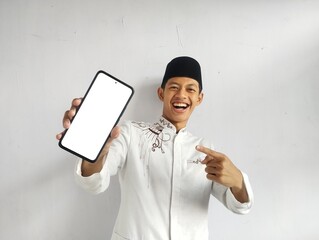 Moslem Asian man smiling and pointing to blank mobile phone screen that he hold