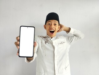 Asian Muslim man shows blank smartphone screen with shocked expression 