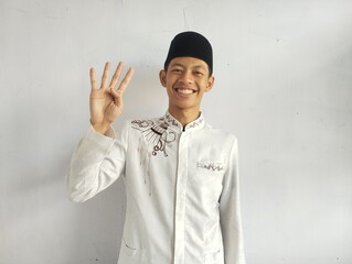 Moslem Asian man smiling at the camera and showing four fingers sign