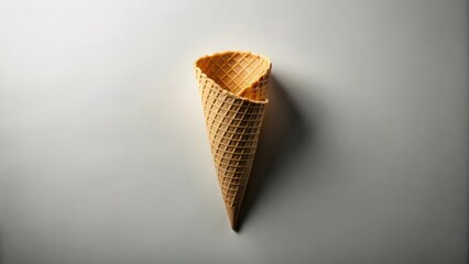 A single, empty waffle cone stands upright against a subtly textured light gray background, a delicious, crispy treat awaiting its sweet, creamy filling.