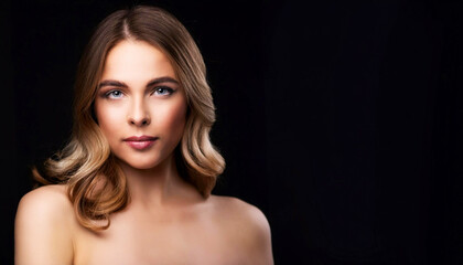 Portrait of a young woman with wavy brown hair, natural makeup, and confident expression, posing against a black background