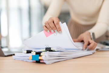Businesswoman hands working in Stacks of paper files for searching and checking unfinished document...
