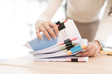 Businesswoman hands working in Stacks of paper files for searching and checking unfinished document...