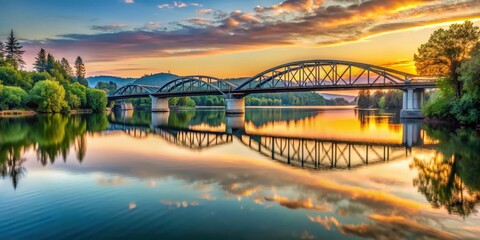 Naklejka premium Bridge over the serene Willamette River in Corvallis at sunset, with trees and hills reflected in the calm waters , nature photography , peaceful atmosphere
