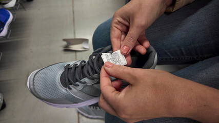A person examines the tongue label of a new running shoe, emphasizing shopping and sizing concerns, perfect for Black Friday