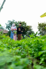 a pair of young Indonesian men and women wearing Muslim clothes walking in the garden going to the Quran. carrying the Quran and prayer tools.