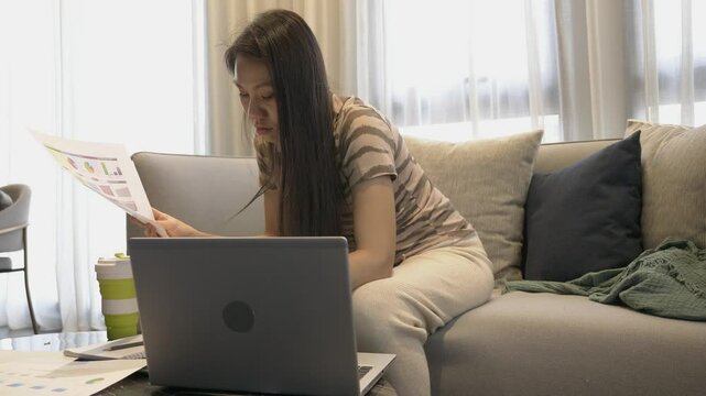 A young professional sits on a couch, focused on analyzing data on her laptop. She reviews charts and graphs, illustrating a modern workspace atmosphere that emphasizes productivity and work-life bala