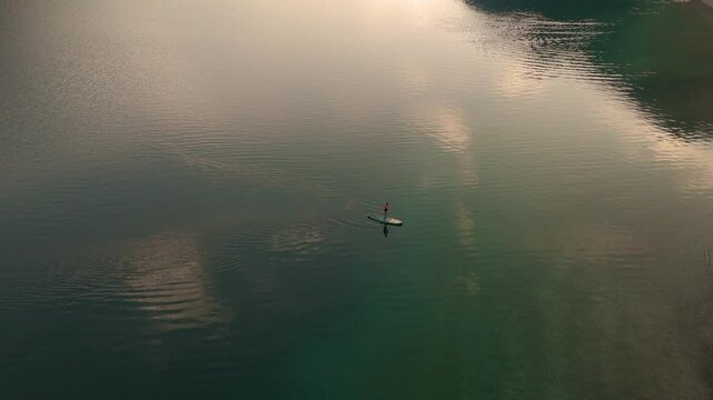 Experience the calm beauty of Plansee Lake in Austria as the sun sets over the crystal-clear waters. woman on supboard at the lake