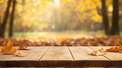 Wooden table with autumn leaves against blurred background of golden foliage