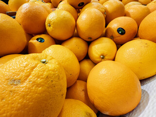 Fresh oranges piled together in a vibrant display at a local market in the morning sun