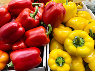 Fresh red and yellow bell peppers stacked for sale at a market stall on a sunny afternoon in autumn