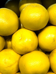 Fresh lemons piled together in a vibrant display at a local market during a sunny afternoon