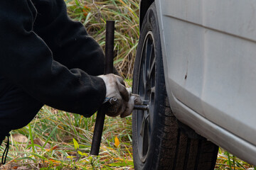Changing a wheel. Close-up of loosening and tightening wheel bolts. Seasonal tire change. Part of...
