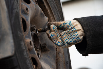 Changing a wheel. Close-up of loosening and tightening wheel bolts. Seasonal tire change. Part of...