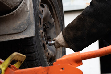 Changing a wheel. Close-up of loosening and tightening wheel bolts. Seasonal tire change. Part of...