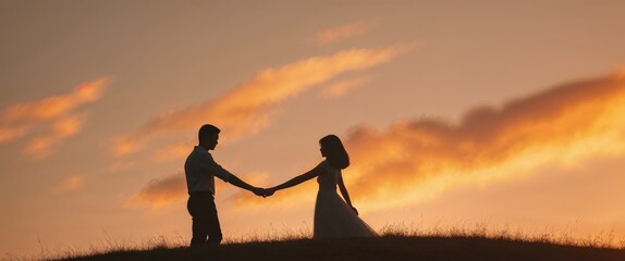 Silhouette of couple holding hands on hilltop at sunset