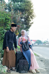 asian muslim couple with suitcase prepare to go. concept of man and woman travelling for eid...