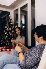 Family Knitting Together Near Christmas Tree in Cozy Home Decorated for Holidays