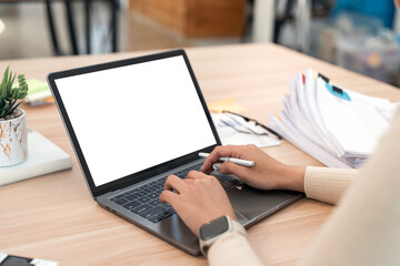 Close-up image of a woman working on laptop computer at a table, typing on the laptop keyboard. the laptop with a white screen mocku