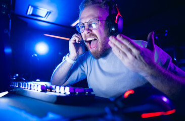 Excited angry caucasian male gamer enjoying online gaming session in dark room. Concept cyber addiction to virtual reality © Parilov