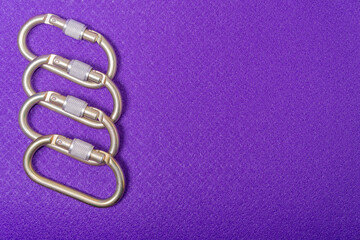 Steel climbing carabiners on a purple background, top view
