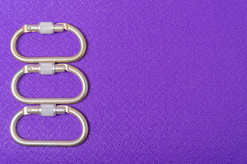 Steel climbing carabiners on a purple background, top view