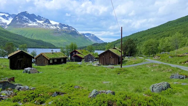 Discover the tranquil charm of Innerdalen Norway countryside, where rustic cabins dot the landscape beneath majestic mountains. Lush greenery and serene waters create a breathtaking backdrop 