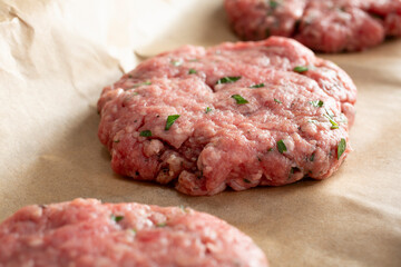 A closeup view of raw ground beef patties on butcher paper.