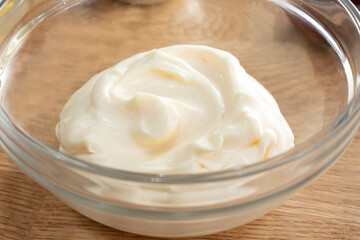 A closeup view of a glass bowl of mayonnaise.