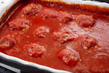 A view of a baking sheet of rice meatballs in marinara.