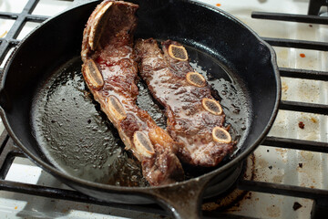 Fototapeta premium A view of a cast iron skillet cooking beef chuck flanken ribs.