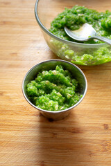 A view of a green shatta sauce in a metal condiment cup.