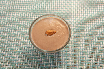 A view of a small glass bowl of bananamilk, topped with an almond.