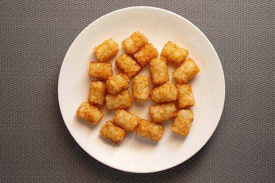 A top down view of a plate of tater tots.